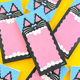 A pile of notepads with a big mouthed black cat designed by YUK FUN